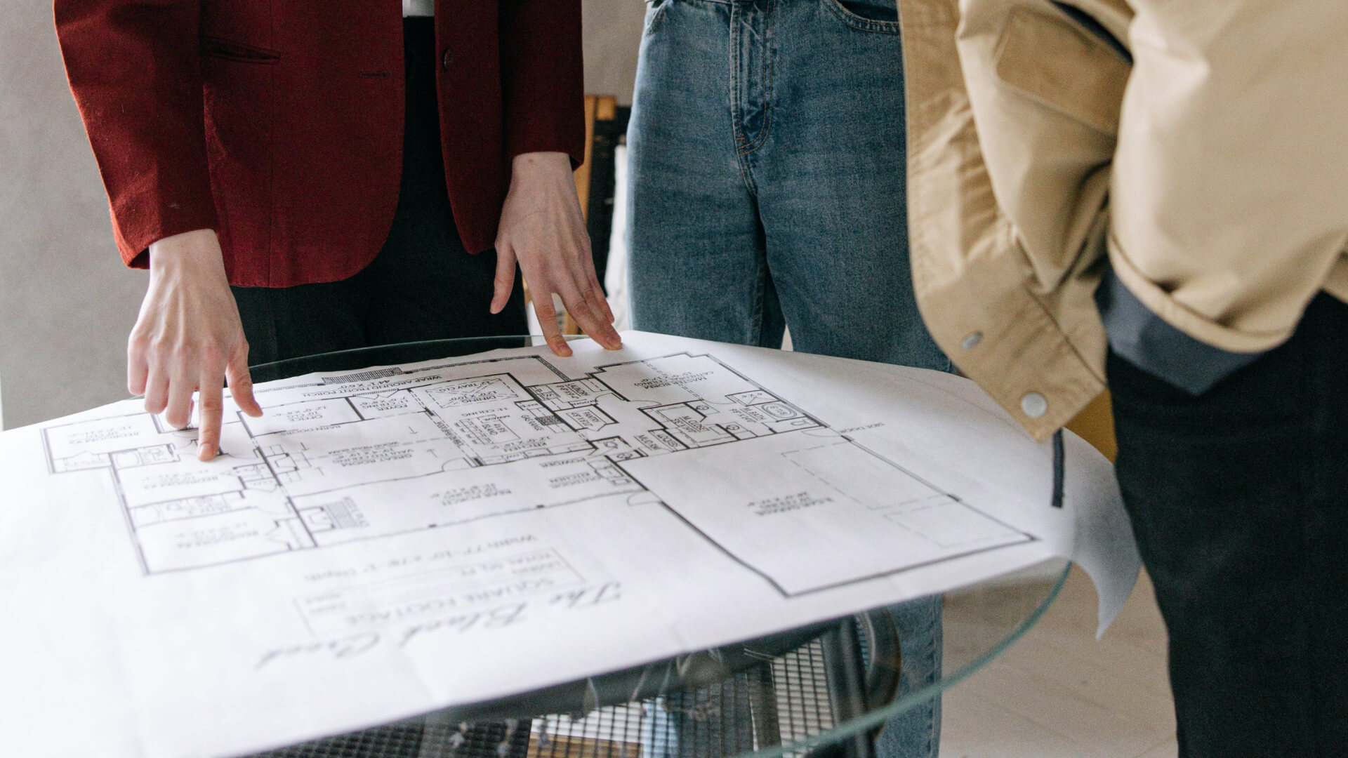 a table with people standing next to it looking at a drawing